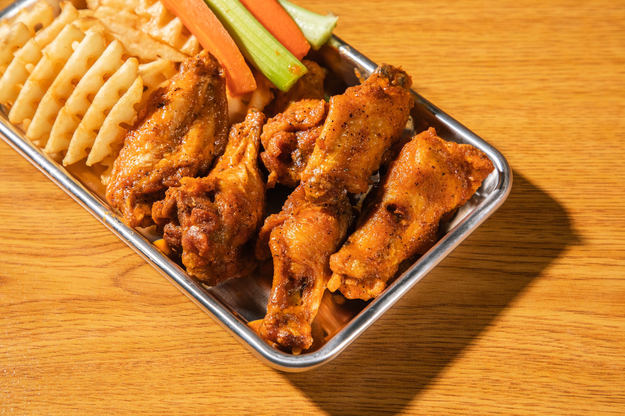 A platter of Wing It wings with celery, carrots and fries
